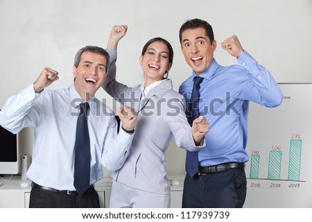 Three happy cheering businesspeople with clenched fists in the offce