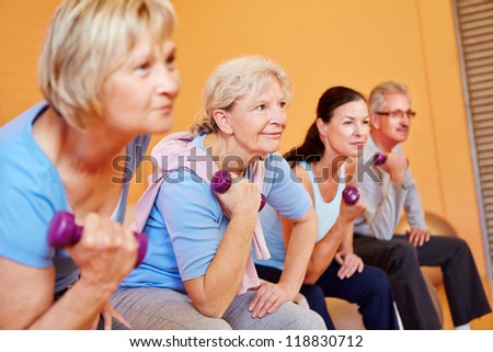 Group of elderly people doing senior sports in fitness center with dumbbells