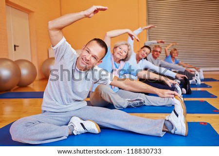 Senior sports class doing stretching exercises in a health club