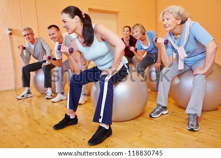 Group of senior citizens doing dumbbell training in gym