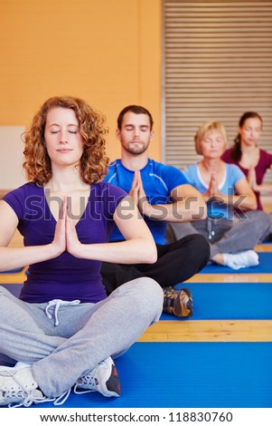 Yoga course with men and women meditating in a fitness center