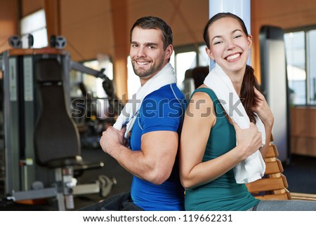 Young happy couple sitting back to back in a health club