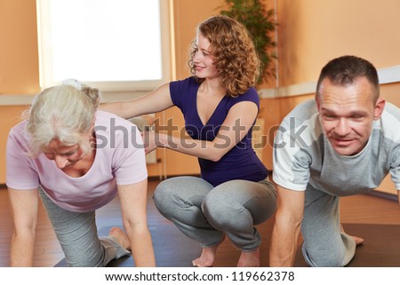 Fitness trainer with senior sports group giving instructions to elderly woman
