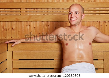 Smiling attractive man sitting relaxed in a sauna