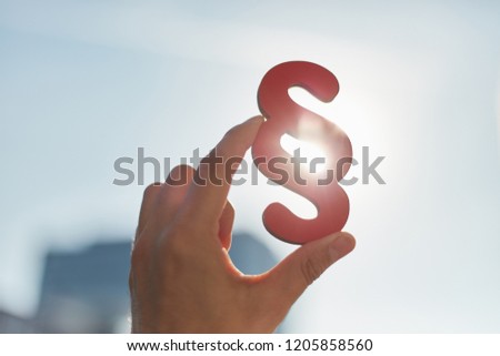 Hand holds paragraphs in the sun as a sign of justice and justice