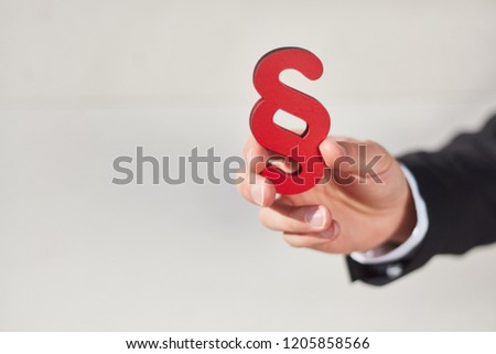 Hand holds a paragraph as a sign of justice and law and law