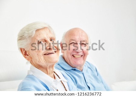 Happy retired couple sitting on the sofa at home or in retirement home