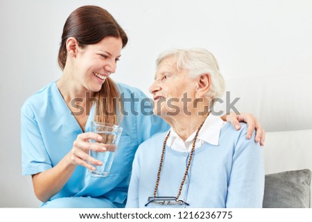 Nursing service Woman gives senior citizen in the nursing home a glass of water or a medicine