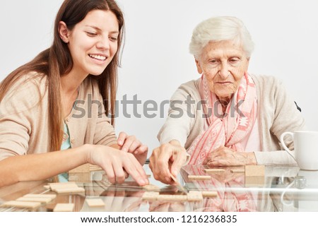 Granddaughter plays domino together with grandmother at home