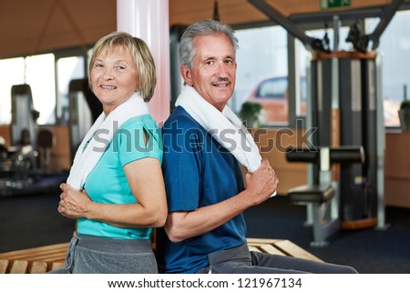 Happy senior couple sitting back to back in a fitness center
