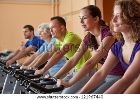 Mixed group riding bikes in spinning class in fitness center