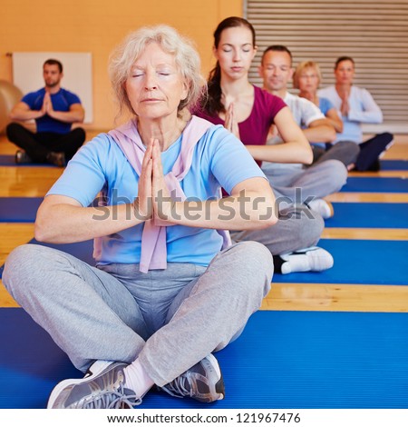 Senior woman doing relaxation exercise in yoga class in a gym