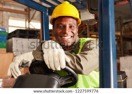 African logistics man as a forklift driver in the warehouse of a freight forwarder