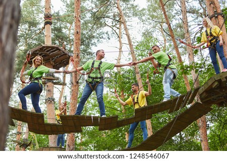 Group helps with climbing in high wire garden as a team training activity