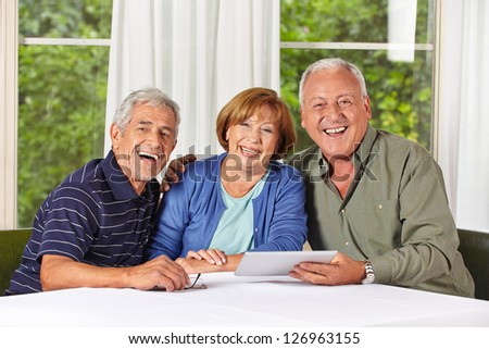 Three happy senior people with tablet computer in a retirement home
