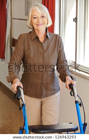 Senior woman walking with walker through a rest home