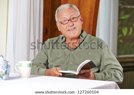 Senior man reading a book with reading glasses in a rest home
