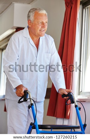 Senior man walking with walker through floors of a clinic