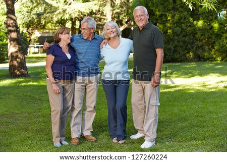 Two happy senior couples standing in the park of a retirement home