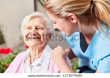 Caring Nurse Caring for Senior Woman in Wheelchair at Nursing Home