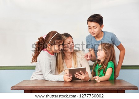 Children and teacher working together on tablet computer in computer science lessons