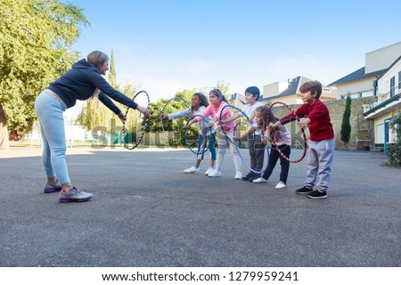 Woman as a sports teacher shows children an exercise with tires in physical education