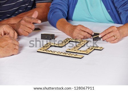 Hands of three old seniors playing a domino game