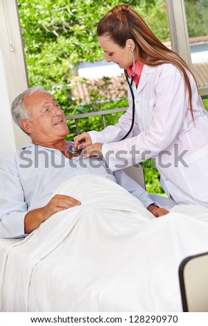 Doctor auscultating patient in hospital bed with stethoscope