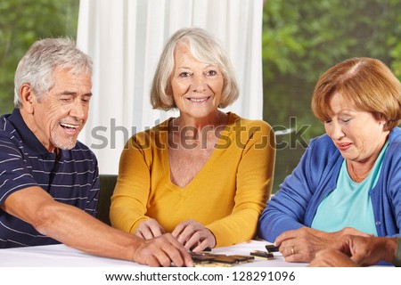 Three senior citizens playing a domino game in a nursing home