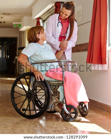 Nurse holding hand of female senior patient in wheelchair