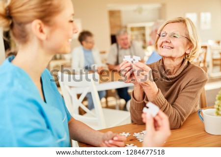 Senior woman with dementia or Alzheimer playing puzzle with a nursing assistant