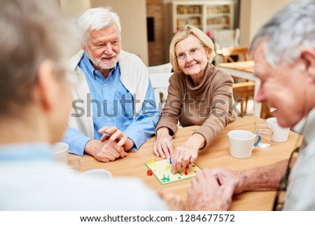 Senior couple and friends have fun playing board game in retirement home or at home