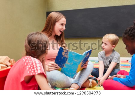 Happy teacher and children reading from a book in preschool or daycare