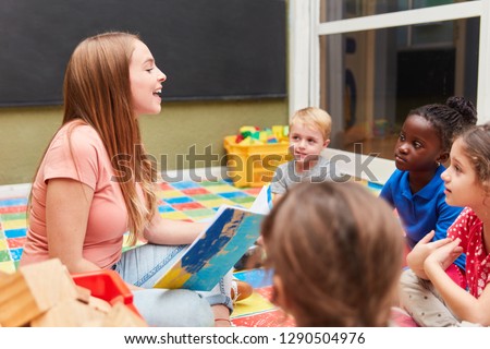 Group of children and kindergarten teacher reading a fairytale book in the day-care center