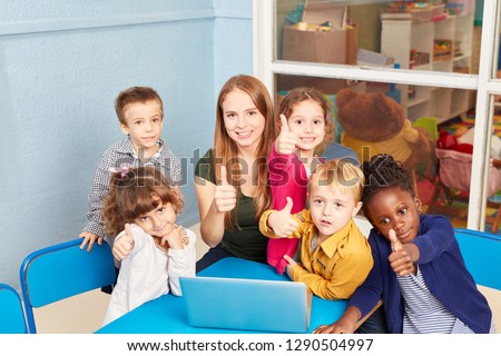 Teacher and children with thumbs up in computer course of preschool or elementary school