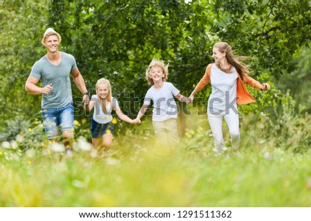 Happy family and kids run together in the garden in summer