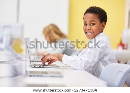 African boy learns computer science at laptop. Computer in elementary school