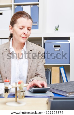Elderly business woman doing tax audit in office with calculator