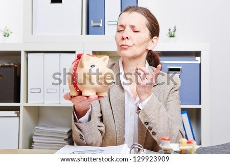 Elderly woman in her office ranting at her piggy bank