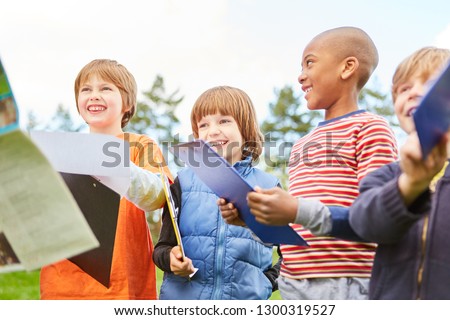 Happy children on a treasure hunt as a scavenger hunt in nature with clipboard