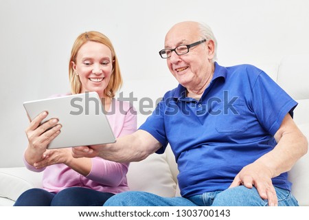 Young woman explains the social network and the video chat to a pensioner on the laptop