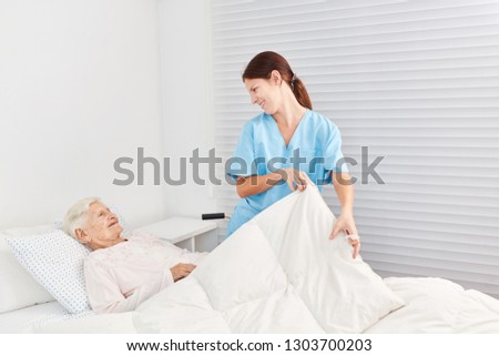 Nurse cares for a sick senior citizen in bed in nursing home or hospice