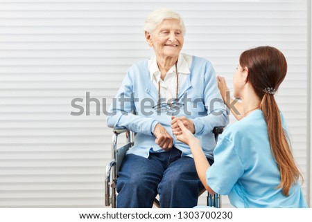 Caring woman on nursing care while nursing a senior citizen in a wheelchair
