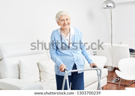 Smiling old woman with walker is learning to walk in her apartment in rehab