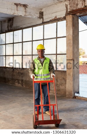 Young logistics worker of a freight forwarding with handcart in an empty hall