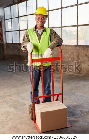 Young logistics worker carries a package on hand truck by mail order