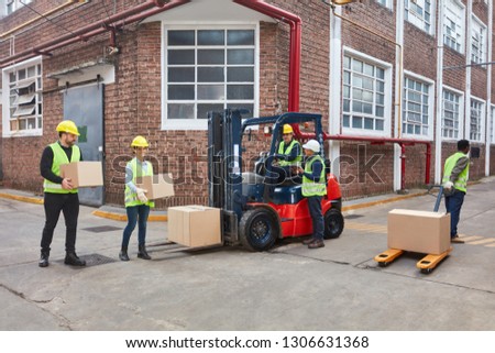 Warehouse workers in front of the logistics center with forklift and many packages
