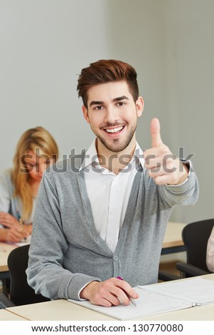 happy young student holding his thumbs up in university class