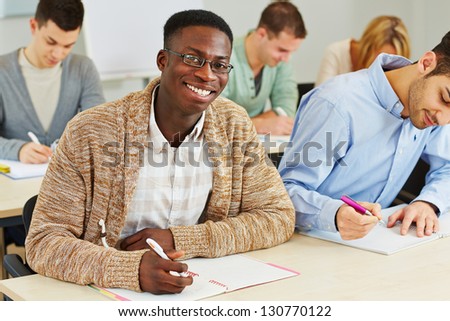 Happy smiling african student taking notes in university class
