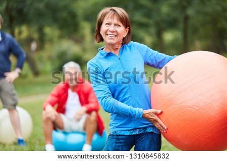 Woman as a physiotherapist with gym ball in front of seniors in her rehab course